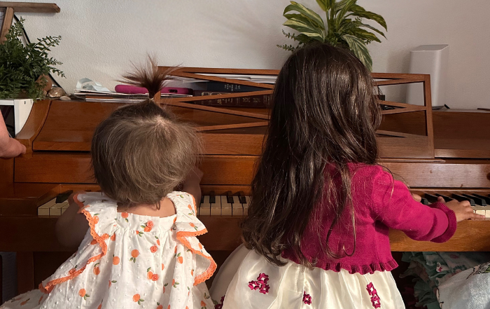 Toddler and baby playing piano together